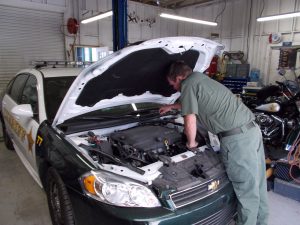 A man working under the hood of a patrol car