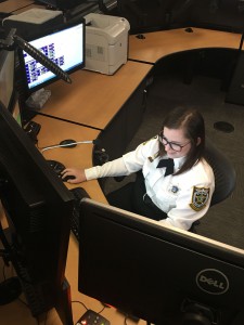 A female officer works on a computer with multiple screens