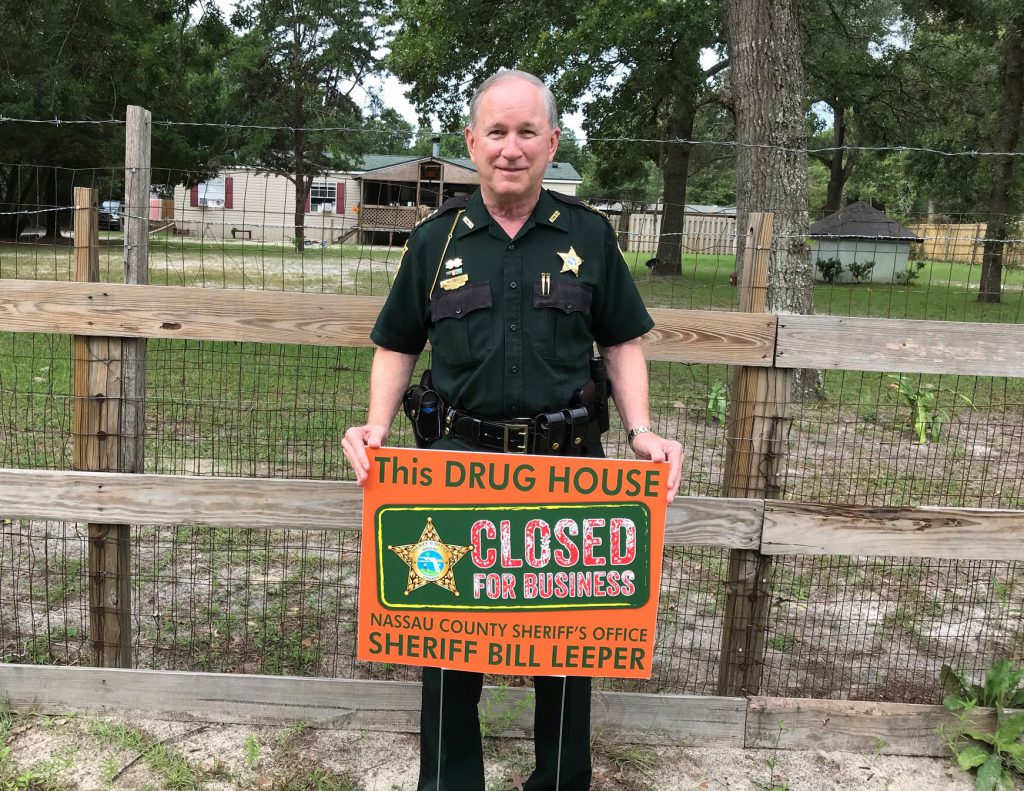 Officer holding Drug House sign